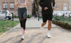 Fit couple jogging together on an urban sidewalk in sportswear.