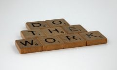 Motivational message spelled out with scrabble tiles on white background.